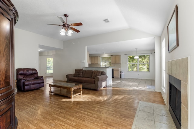 living room with ceiling fan, light hardwood / wood-style floors, and lofted ceiling