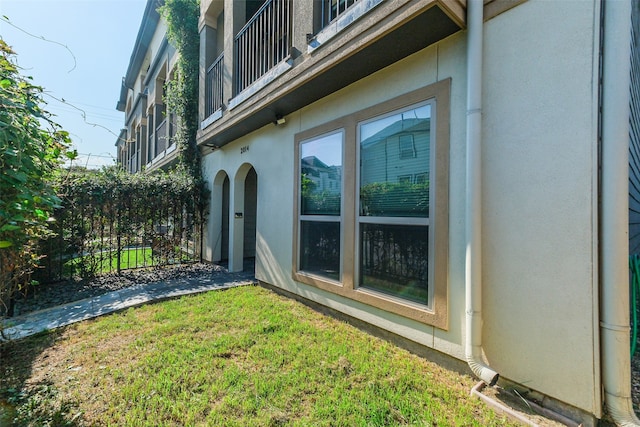 view of home's exterior featuring a balcony and a lawn