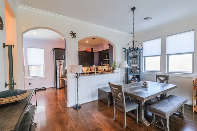 dining area with dark hardwood / wood-style floors, a wealth of natural light, and ornamental molding