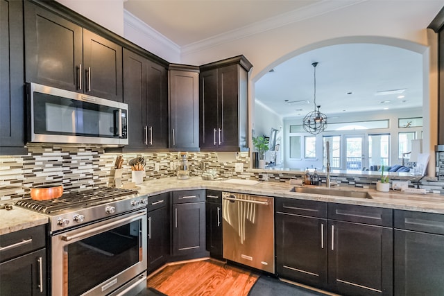 kitchen with sink, light hardwood / wood-style flooring, crown molding, decorative backsplash, and appliances with stainless steel finishes