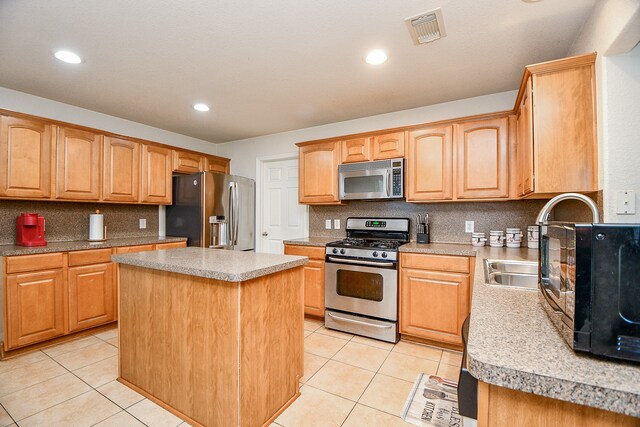 kitchen featuring appliances with stainless steel finishes, a kitchen island, and light tile patterned flooring