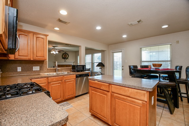 kitchen with a wealth of natural light, a center island, black appliances, and sink