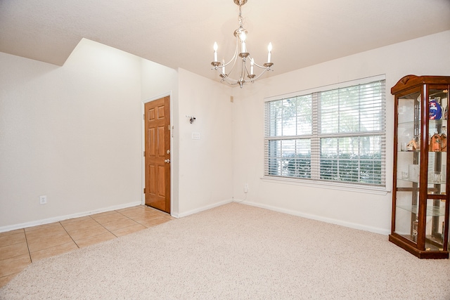 tiled spare room featuring an inviting chandelier