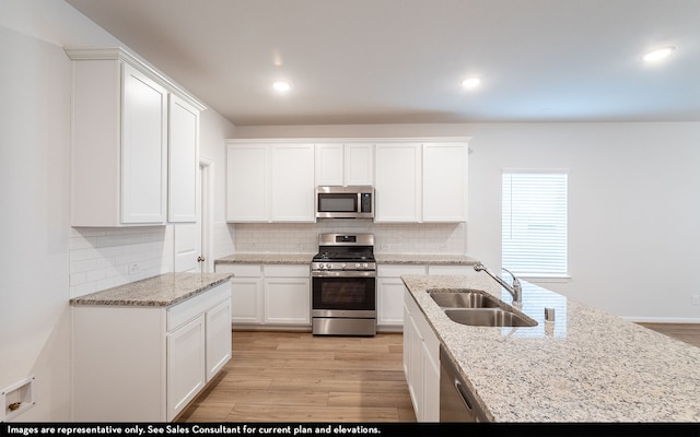 kitchen with white cabinetry, sink, stainless steel appliances, and light hardwood / wood-style floors