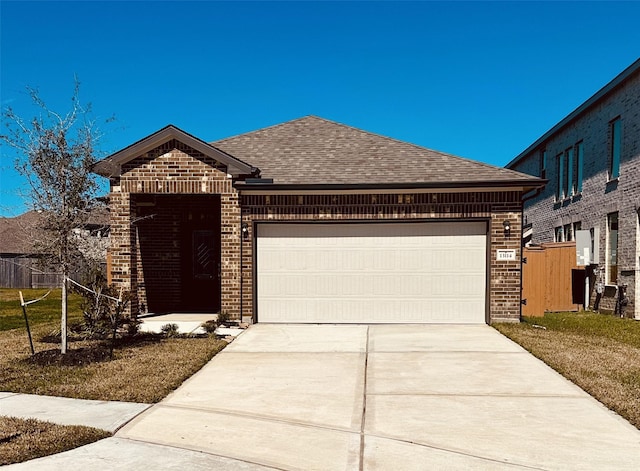 french provincial home with a shingled roof, brick siding, driveway, and an attached garage