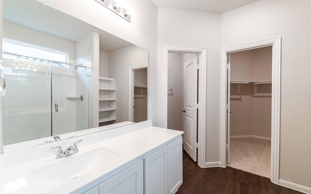 13101 Sapphire Lake Ln, Texas City, TX 77568 - full bathroom with wood finished floors, a walk in closet, vanity, a shower stall, and baseboards