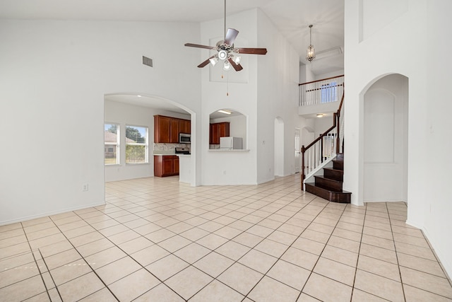 unfurnished living room featuring ceiling fan, high vaulted ceiling, and light tile patterned floors