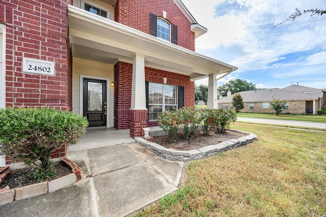 doorway to property featuring a porch and a yard