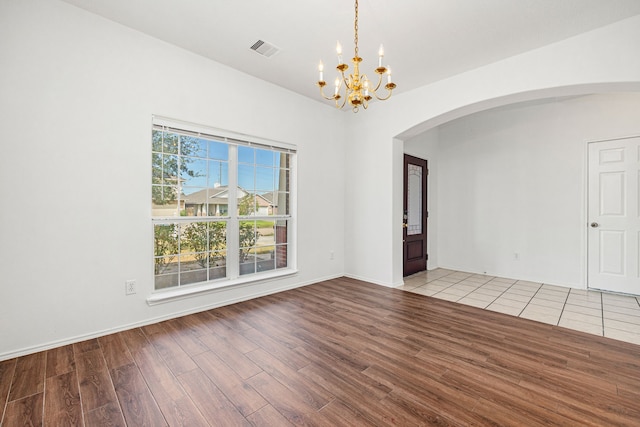 unfurnished room with light hardwood / wood-style floors and an inviting chandelier