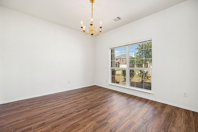 spare room featuring dark hardwood / wood-style flooring and an inviting chandelier