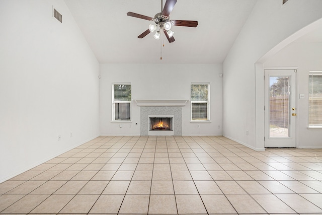 unfurnished living room featuring ceiling fan, a fireplace, light tile patterned flooring, and high vaulted ceiling