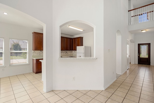 kitchen with tasteful backsplash, light tile patterned flooring, and white refrigerator