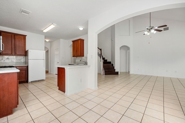 kitchen with white refrigerator, backsplash, ceiling fan, and light tile patterned flooring