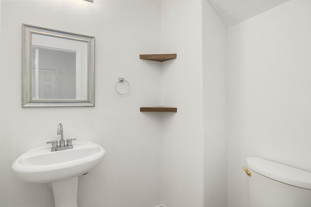 bathroom featuring a textured ceiling, toilet, and sink