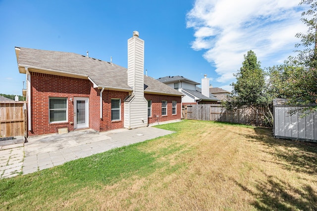 back of property featuring a patio area, a yard, and a storage unit