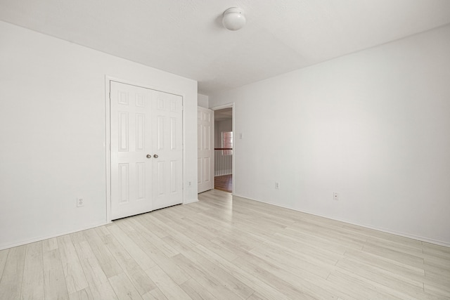 unfurnished bedroom featuring light wood-type flooring and a closet