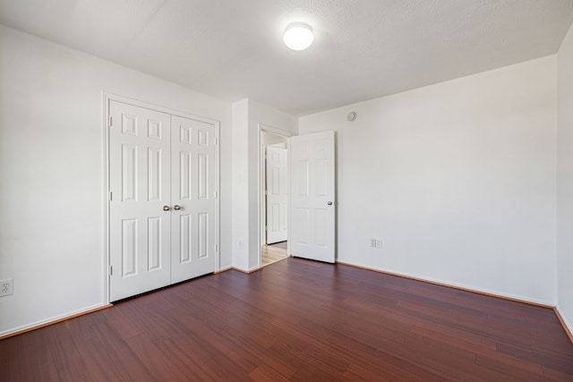 unfurnished bedroom with a textured ceiling, a closet, and dark hardwood / wood-style floors