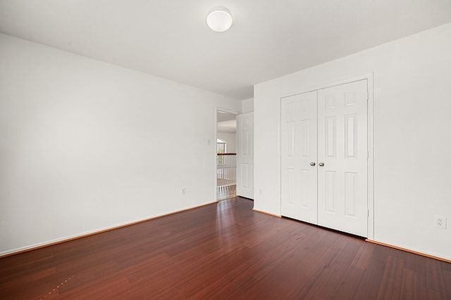 unfurnished bedroom with a closet and dark wood-type flooring