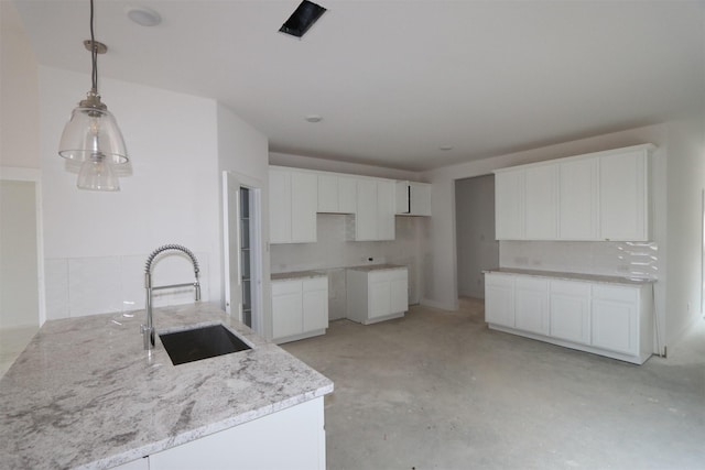 kitchen featuring decorative light fixtures, white cabinetry, a sink, light stone countertops, and concrete floors