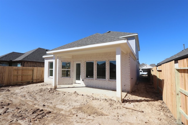 back of house with a patio, brick siding, roof with shingles, and a fenced backyard