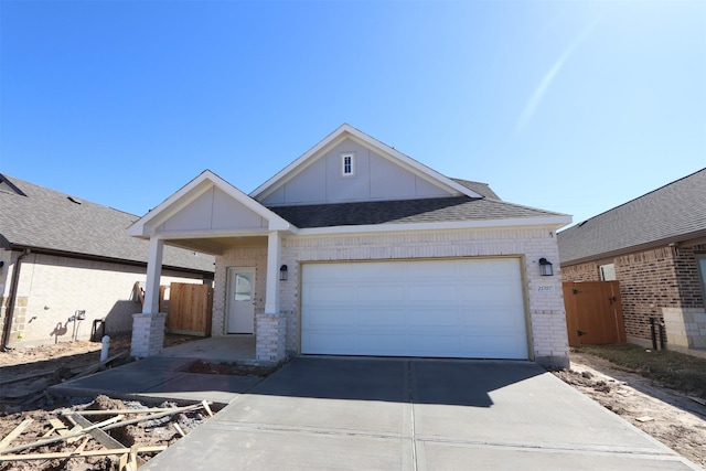 view of front of home featuring fence, roof with shingles, concrete driveway, an attached garage, and brick siding