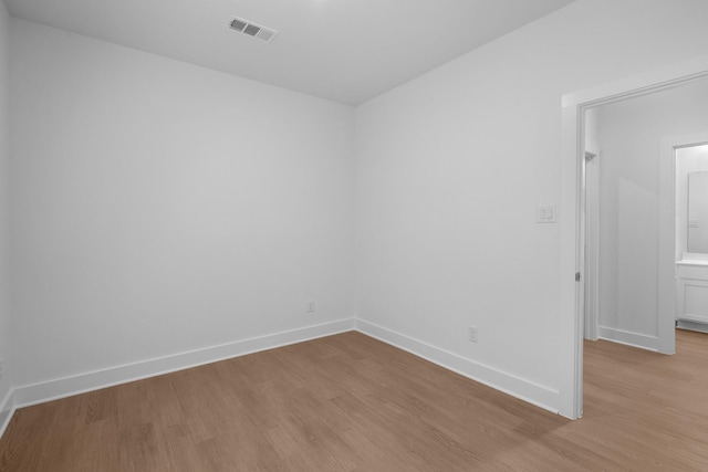 unfurnished room featuring visible vents, light wood-style flooring, and baseboards