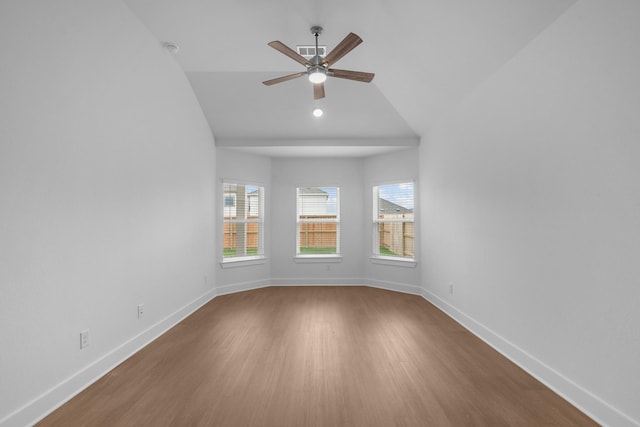 empty room featuring visible vents, wood finished floors, baseboards, ceiling fan, and vaulted ceiling