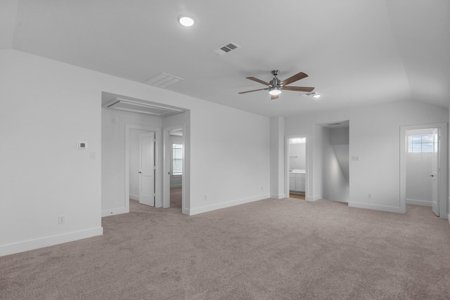 unfurnished bedroom featuring light carpet, attic access, baseboards, vaulted ceiling, and visible vents