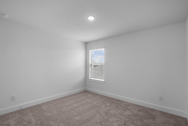 empty room featuring baseboards and light colored carpet
