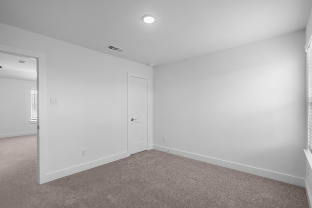empty room featuring carpet floors, baseboards, and visible vents