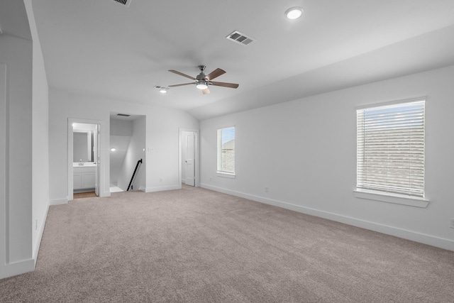 spare room with light carpet, a ceiling fan, baseboards, lofted ceiling, and visible vents