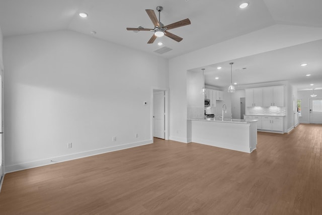 unfurnished living room featuring a sink, a ceiling fan, recessed lighting, lofted ceiling, and visible vents
