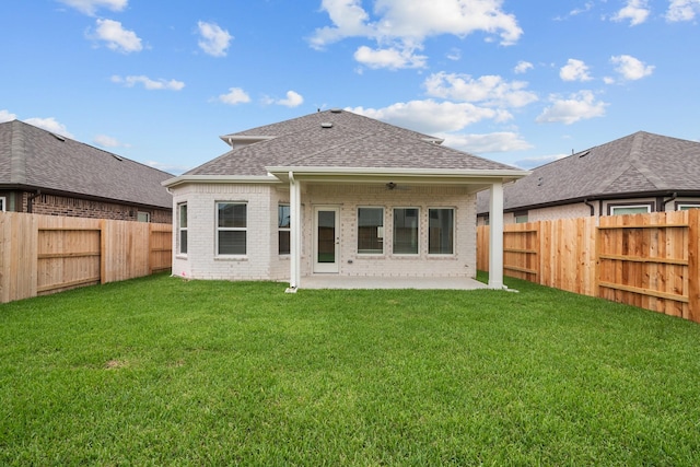 back of house featuring roof with shingles, brick siding, a fenced backyard, a patio area, and a yard