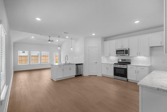 kitchen with backsplash, appliances with stainless steel finishes, a sink, a peninsula, and open floor plan