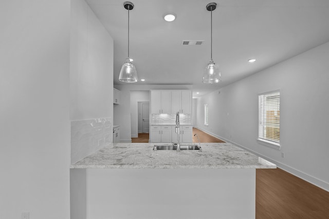 kitchen featuring white cabinets, a sink, recessed lighting, baseboards, and visible vents