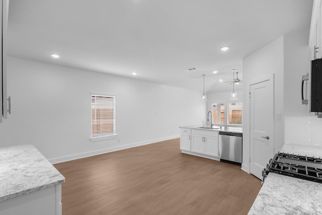kitchen featuring appliances with stainless steel finishes, wood finished floors, a sink, white cabinets, and recessed lighting