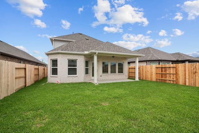 back of house with a patio, a fenced backyard, brick siding, a shingled roof, and a lawn
