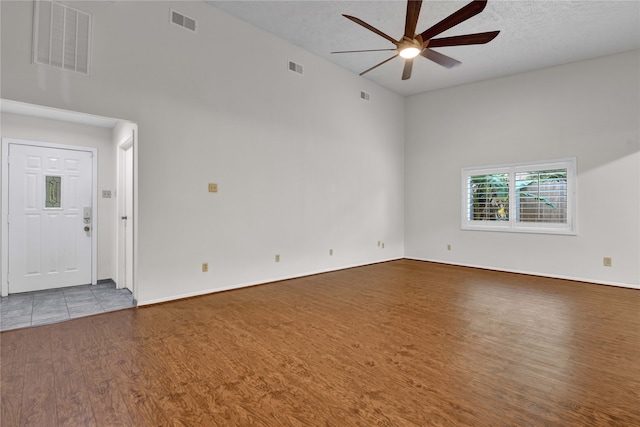 unfurnished living room featuring a textured ceiling, hardwood / wood-style flooring, high vaulted ceiling, and ceiling fan