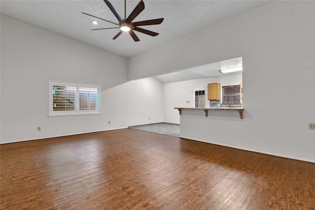 unfurnished living room featuring ceiling fan, dark hardwood / wood-style flooring, and a textured ceiling