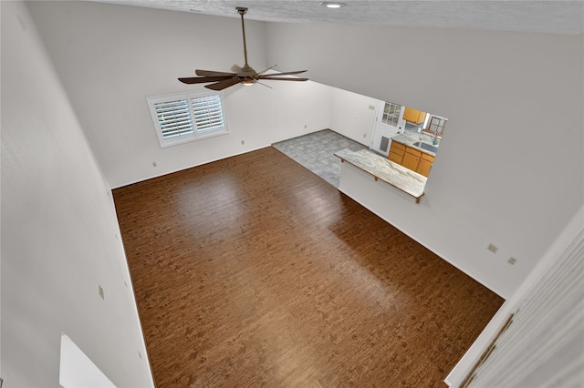 unfurnished living room featuring ceiling fan, high vaulted ceiling, wood-type flooring, and a textured ceiling