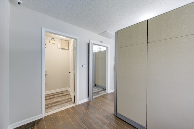 hallway with a textured ceiling and dark hardwood / wood-style flooring