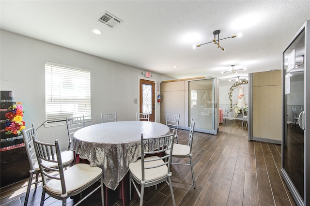 dining space featuring a textured ceiling, a chandelier, and dark hardwood / wood-style floors