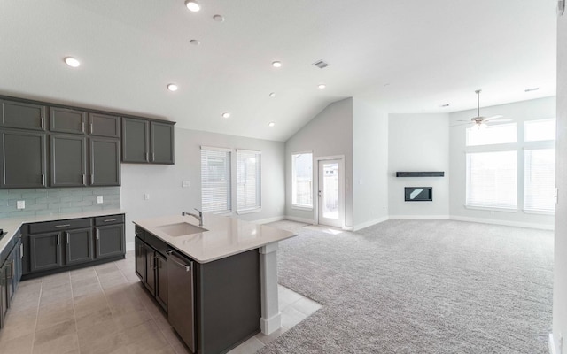 kitchen featuring light carpet, sink, a wealth of natural light, and a center island with sink