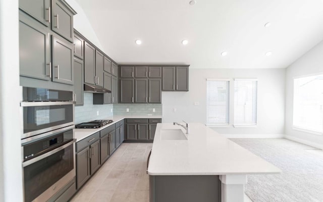 kitchen featuring a center island with sink, sink, stainless steel oven, and gas cooktop