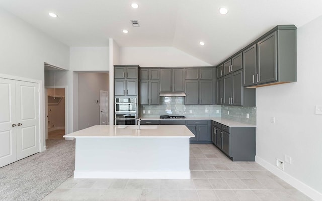 kitchen featuring gray cabinetry, tasteful backsplash, and an island with sink