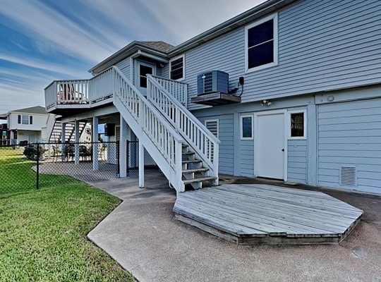 rear view of property featuring a yard, central AC unit, and a wooden deck