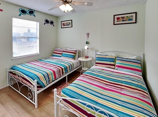 bedroom with a textured ceiling, hardwood / wood-style flooring, and ceiling fan