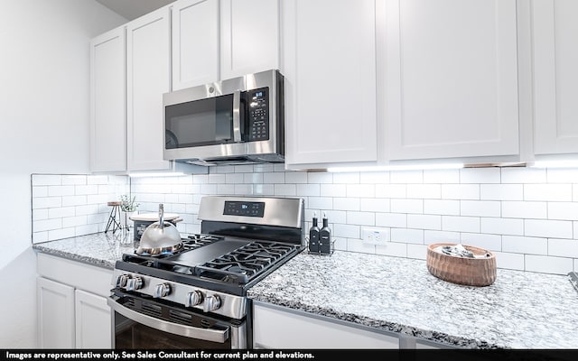 kitchen featuring tasteful backsplash, light stone countertops, white cabinets, and stainless steel appliances