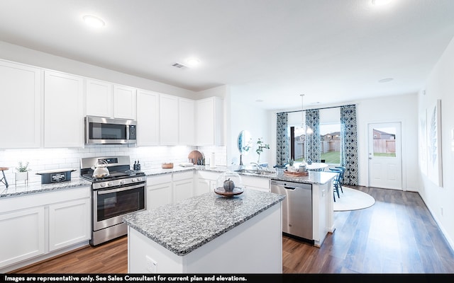 kitchen with dark hardwood / wood-style flooring, stainless steel appliances, white cabinets, a center island, and hanging light fixtures