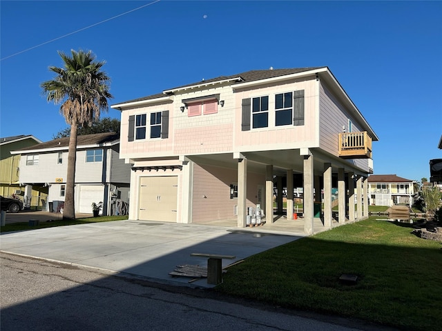 coastal inspired home featuring a garage, concrete driveway, a front lawn, and roof with shingles